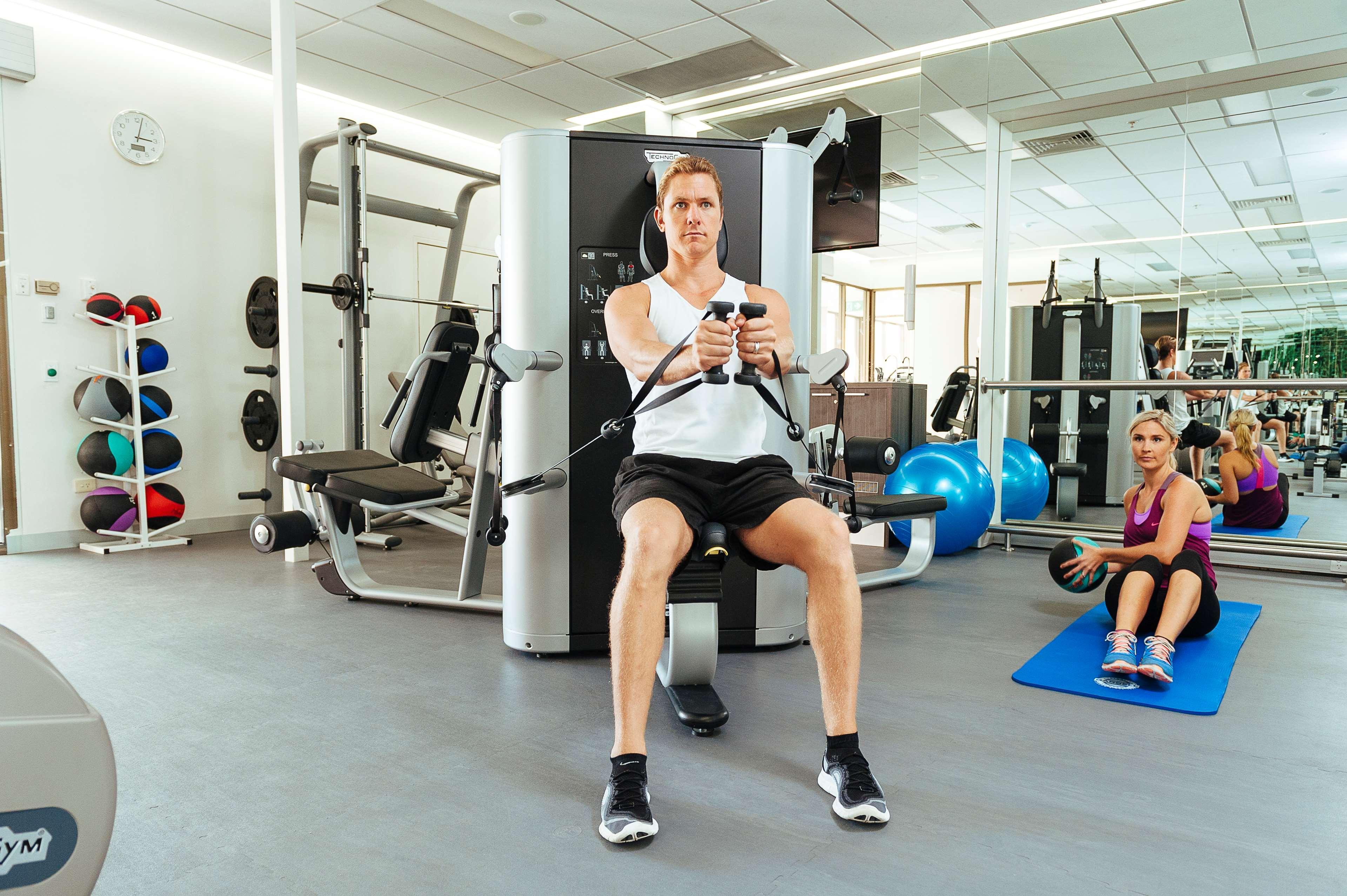 Stamford Plaza Adelaide Hotell Eksteriør bilde The photo shows a gym setting with two individuals engaged in workout activities. 

In the foreground, a man is seated on a machine, using the handles to perform a rowing exercise. He is wearing a sleeveless shirt and shorts, indicating an active wor