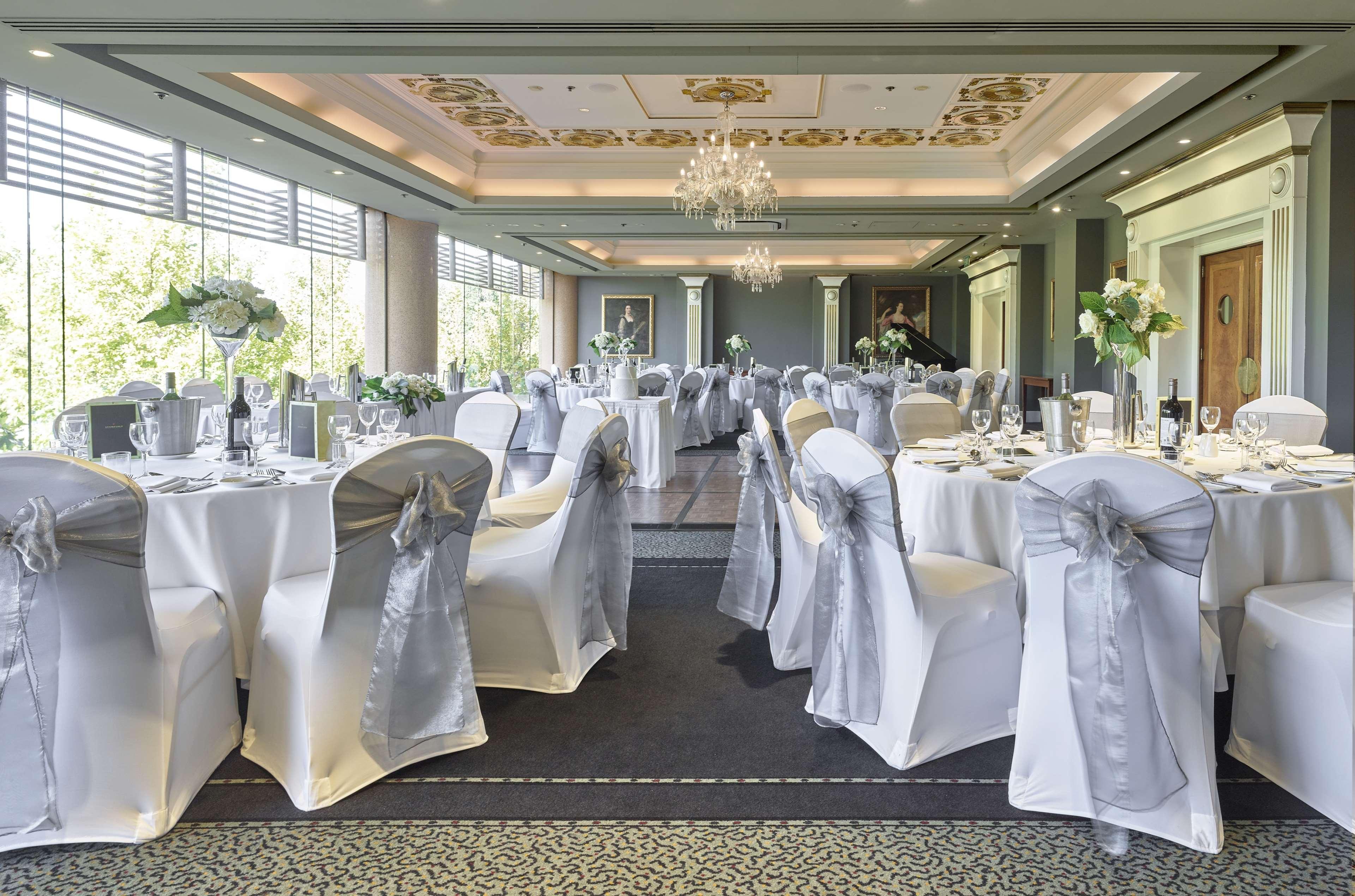 Stamford Plaza Adelaide Hotell Eksteriør bilde The photo displays an elegantly arranged banquet hall. The room features several round tables covered with white tablecloths, each adorned with silver sashes on the chairs. There are floral centerpieces, possibly white flowers, on the tables, adding 