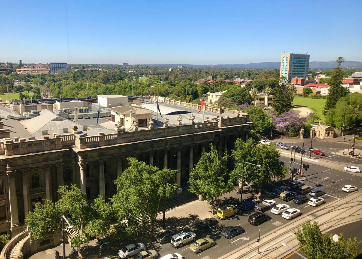 Stamford Plaza Adelaide Hotell Eksteriør bilde The photo depicts a cityscape view, showcasing a mix of architectural structures and greenery. In the foreground, there is a large, classical building with columns, suggesting it may be a historical or governmental structure. Surrounding the building
